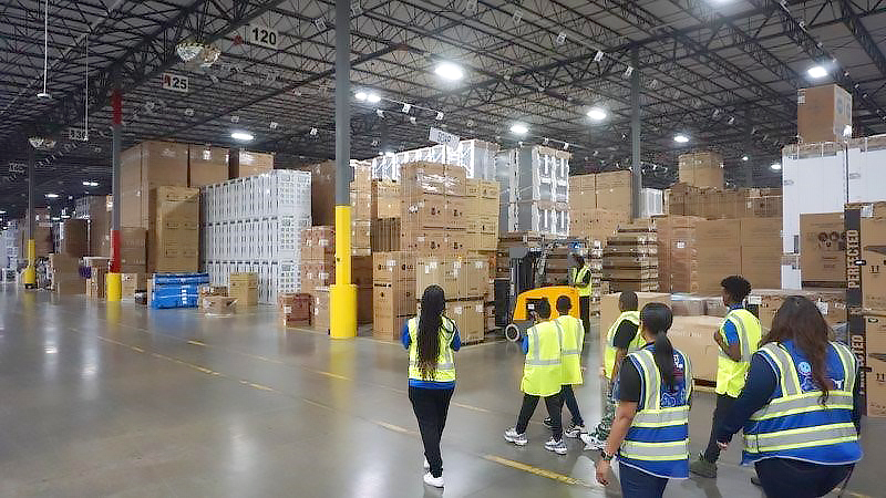 Teens tour a Best Buy distribution center with an employee.